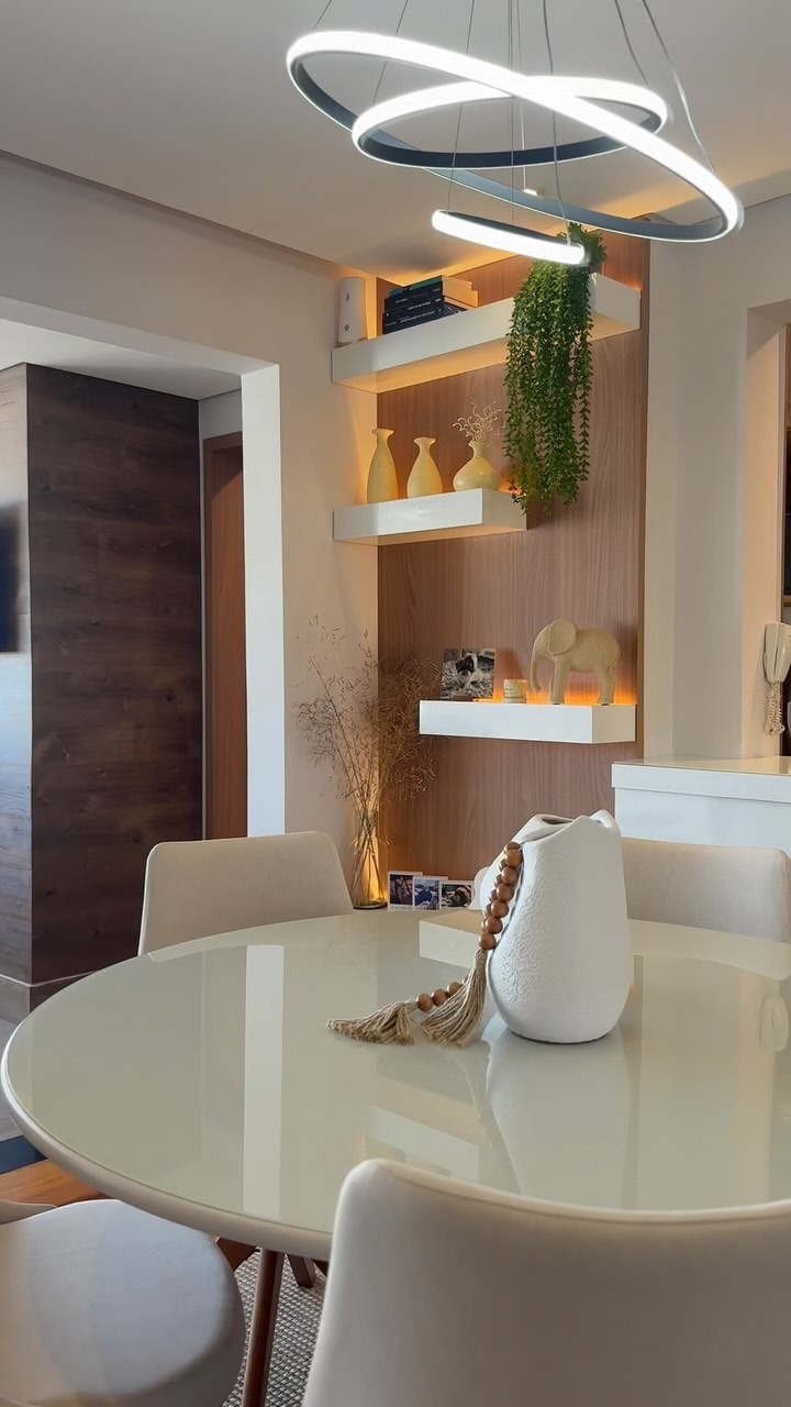 Sala de jantar com luminária circular, prateleiras iluminadas e mesa redonda — projeto de interiores da bulb arquitetura